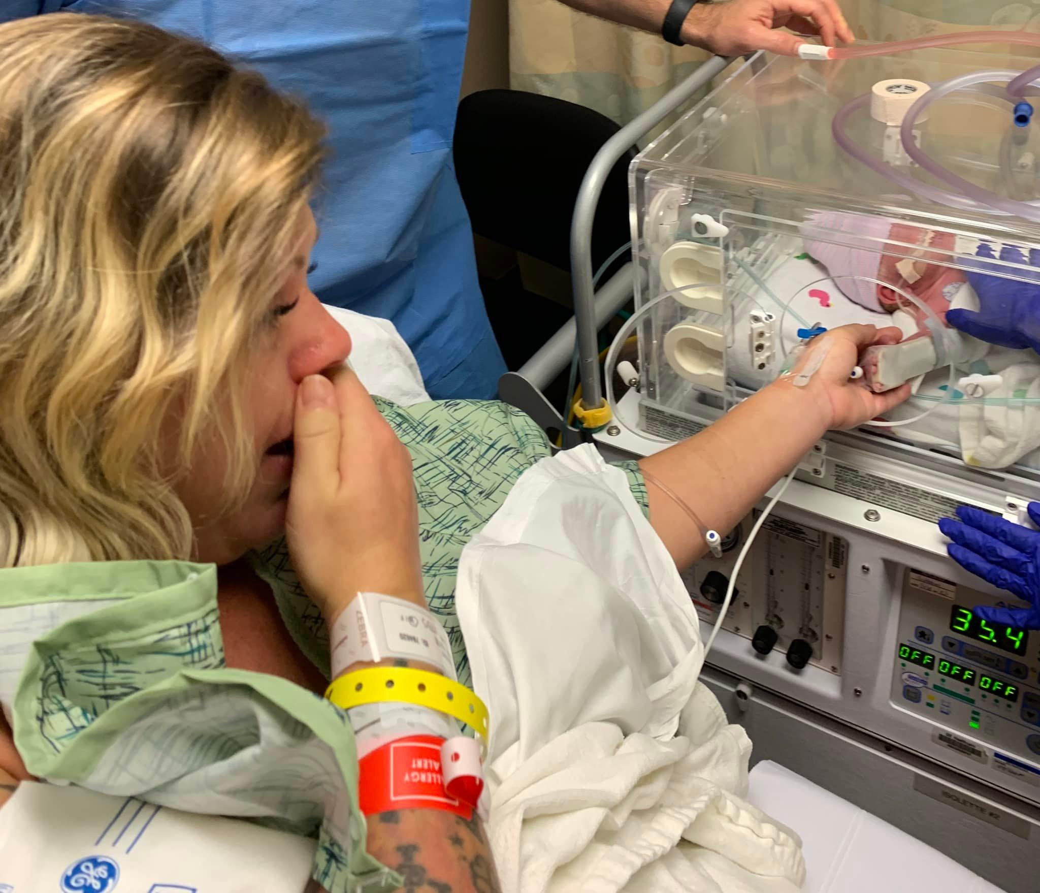 Photo of mom reaching out to touch the baby. KuoJen Tsao, MD, made sure mom Kate Ferrell could see Tristan right after birth. (Photo by Rick Oliver)